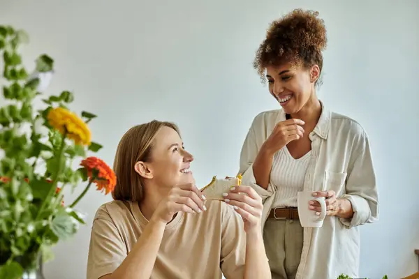 Due partner condividono risate e cibo in un'atmosfera luminosa e invitante. — Foto stock