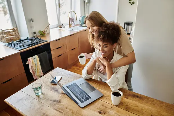 Una coppia gioiosa condivide sorrisi su un computer portatile sorseggiando caffè. — Foto stock