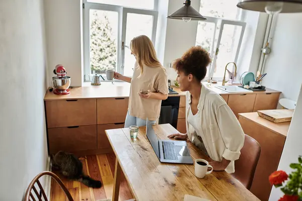 A cheerful couple shares a lovely morning, sipping drinks and working at their kitchen table. — Stock Photo