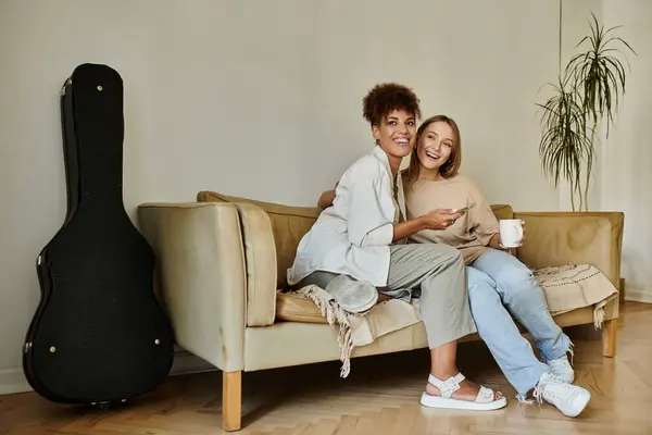 A happy couple shares laughter and warmth while sipping tea on a comfortable couch. — Stock Photo