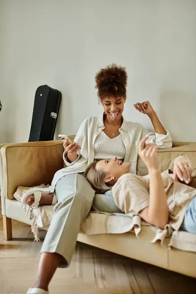 Dois parceiros desfrutam de momentos lúdicos em um sofá, abraçando amor e riso. — Fotografia de Stock