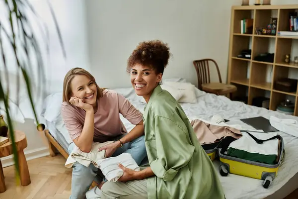 Two partners share laughter while folding clothes in their vibrant space. — Stock Photo