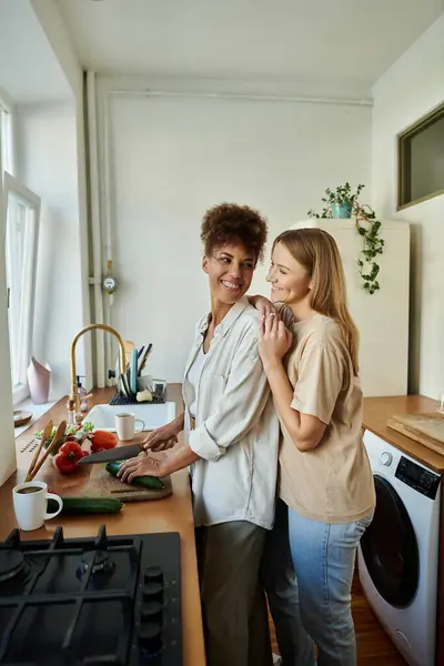 A joyful couple prepares a meal while sharing affectionate moments. — Stock Photo