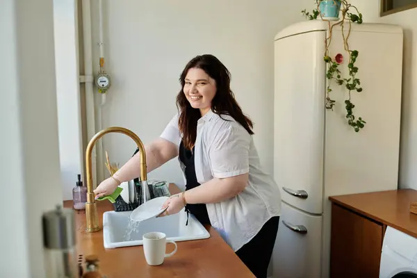 Eine fröhliche Frau spült gerne Geschirr in ihrer gemütlichen Wohnküche. — Stockfoto