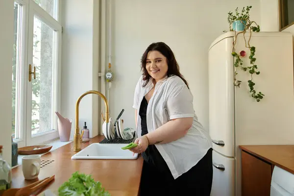 A cheerful woman prepares fresh vegetables in a sunny kitchen. — Stock Photo