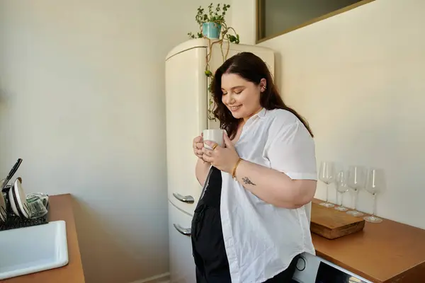 Una donna allegra assapora il suo caffè mattutino a casa, abbracciando la sua bellezza e comfort. — Foto stock