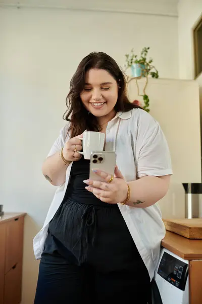 A plus size woman savoring coffee and browsing on her smartphone. — Stock Photo