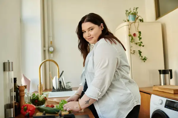 A vibrant woman joyfully prepares fresh vegetables in her inviting kitchen. — Stock Photo
