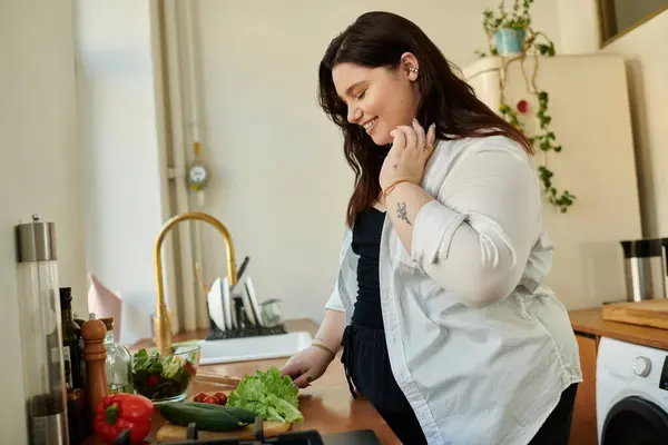 A woman happily arranging fresh vegetables while cooking at home. — Stock Photo
