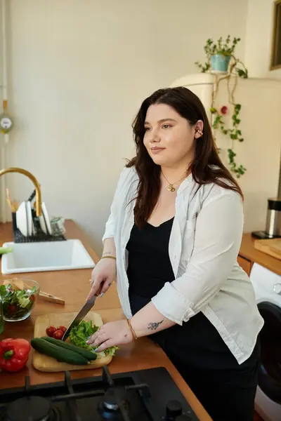 Mulher alegremente cortar legumes em sua cozinha quente e convidativa. — Fotografia de Stock