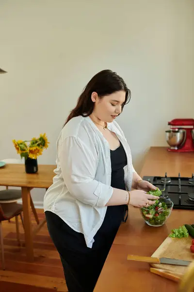 A plus size woman prepares a vibrant salad in her cozy kitchen. — Stock Photo