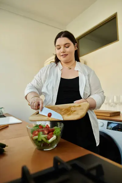 Рубка свежих овощей, чтобы приготовить вкусный салат в ее уютной кухне. — стоковое фото