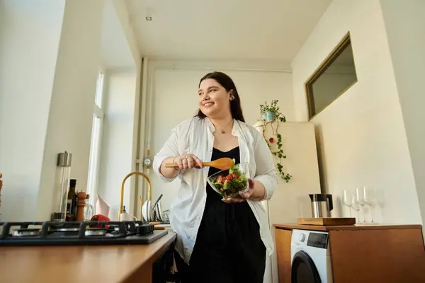 A plus size woman happily chops vegetables in her cozy kitchen. — Stock Photo