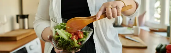 Uma mulher alegre mistura uma salada vibrante em sua cozinha acolhedora. — Fotografia de Stock