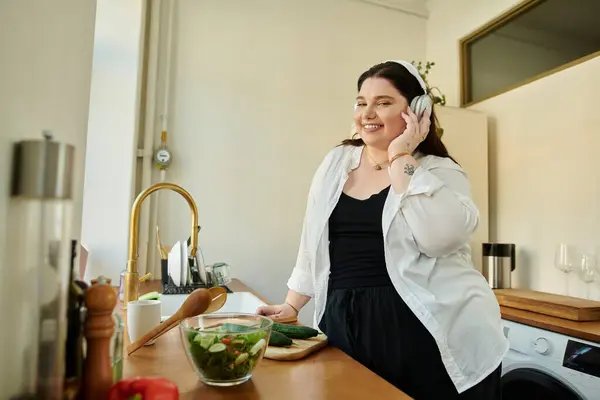 Woman enjoys preparing a vibrant salad while smiling in her modern kitchen. — Stock Photo