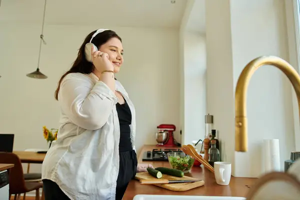 A cheerful woman enjoys cooking while chatting on the phone. — Stock Photo