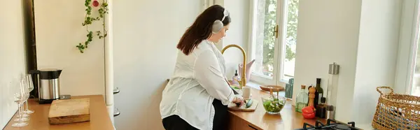 Woman joyfully prepares a fresh meal while enjoying her bright kitchen. — Stock Photo