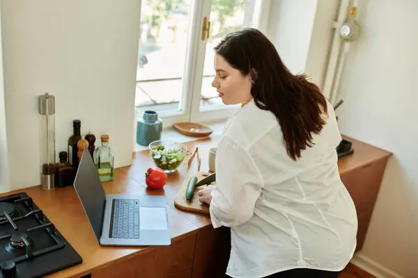 Une femme prépare des ingrédients frais tout en travaillant dans sa cuisine confortable. — Photo de stock