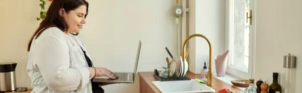 Uma mulher plus size gosta de trabalhar em seu laptop em sua cozinha encantadora. — Fotografia de Stock