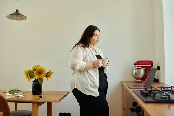 A lovely woman savors her coffee in a warm, inviting kitchen filled with sunflowers. — Stock Photo