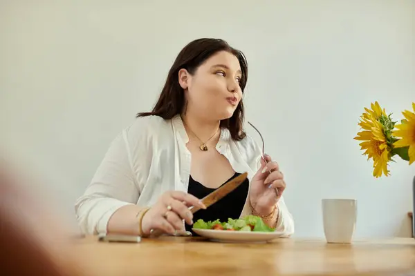Eine Frau genießt an ihrem gemütlichen Esstisch einen lebhaften Salat. — Stockfoto