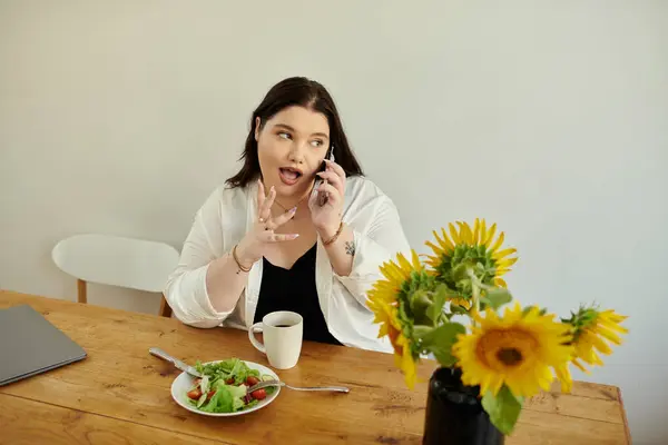 A cheerful woman talks on the phone while having a refreshing meal. — Stock Photo