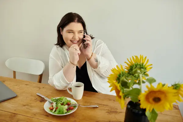 Charming woman smiles while talking on the phone, enjoying a healthy lunch. — Stock Photo