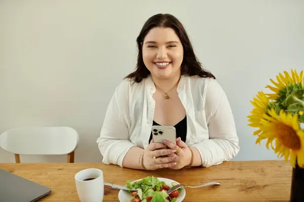 Smiling woman relaxes while having lunch and chatting on her phone. — Stock Photo