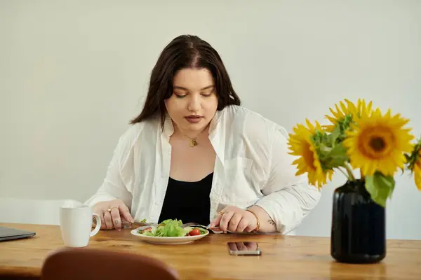 Eine Plus-Size-Frau genießt einen frischen Salat am Esstisch. — Stockfoto