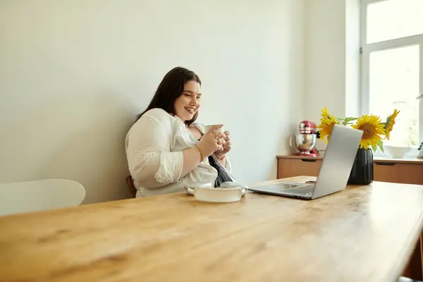 A plus size woman relaxes at home with coffee and her laptop. — Stock Photo
