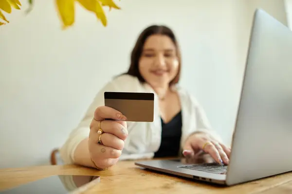 Smiling woman holds a credit card while shopping online at her cozy table. — Stock Photo
