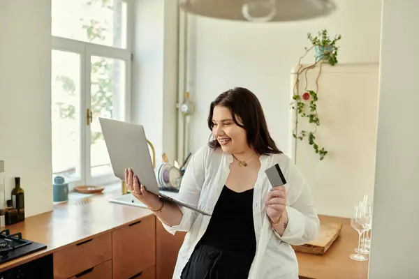 A cheerful woman enjoys online shopping while relaxing in her cozy kitchen. — Stock Photo