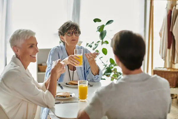 A joyful family enjoys breakfast together, sharing laughter and conversation over pancakes and juice. — Stock Photo