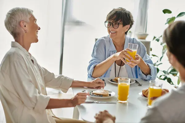 A cozy morning as lesbian parents enjoy breakfast with their adult son, filled with laughter and connection. — Stock Photo