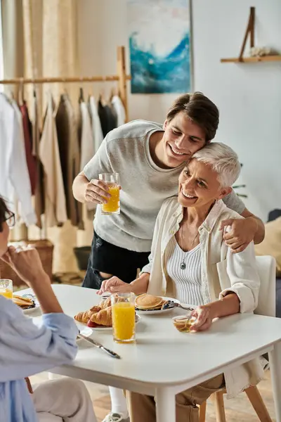 Lesbian parents and their adult son enjoy a sunny breakfast filled with laughter and togetherness. — Stock Photo