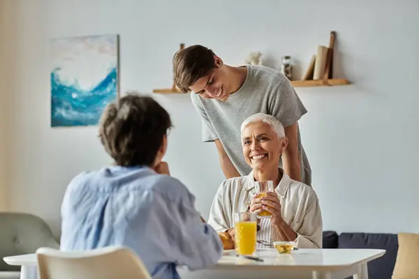 Eine fröhliche Familie frühstückt zusammen und teilt Lachen und Liebe bei Drinks und Gesprächen. — Stockfoto