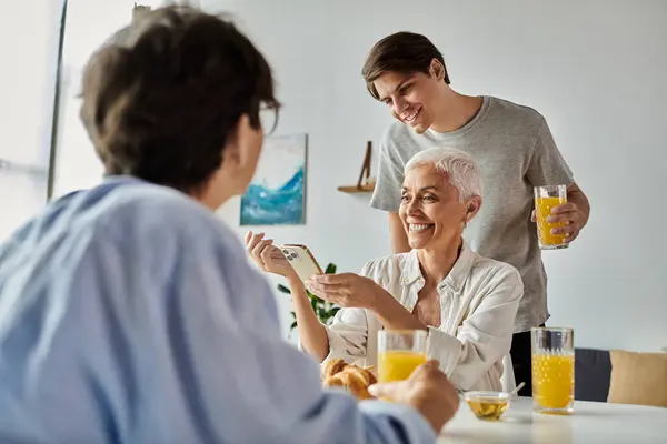 A loving LGBTQ family shares a cheerful breakfast, enjoying laughter and conversation over fresh juice and pastries. — Stock Photo