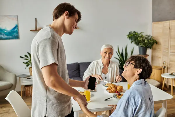 A loving LGBTQ family enjoys breakfast, sharing smiles and conversation around the dining table. — Stock Photo