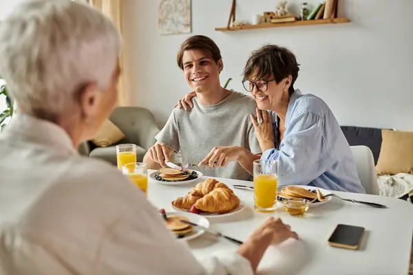 A loving family shares smiles and breakfast at their dining table, enjoying pancakes and conversation. — Stock Photo