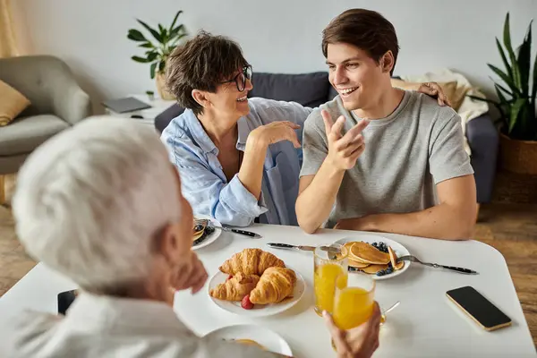 Uma família LGBTQ amorosa desfruta de um delicioso café da manhã, compartilhando risos e histórias ao redor da mesa. — Fotografia de Stock