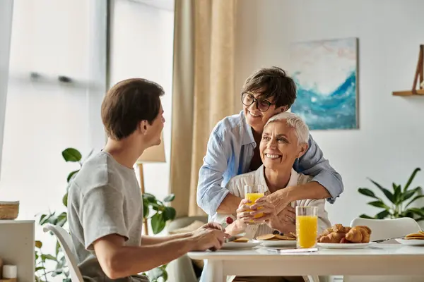 Les parents lesbiennes et leur fils adulte partagent un petit déjeuner chaud rempli de rire et d'amour. — Photo de stock