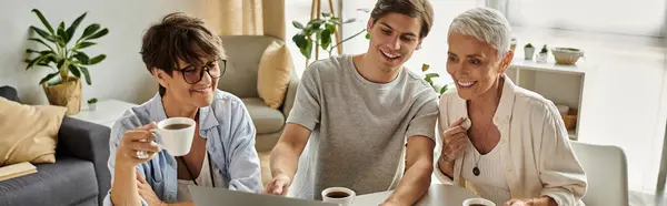 Lesbian parents share laughter and coffee with their adult son during a heartwarming afternoon. — Stock Photo