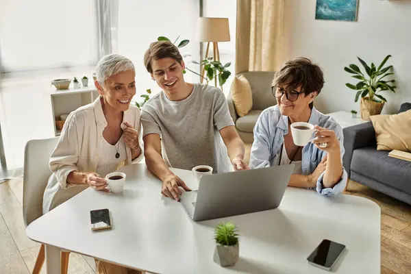 Drei Familienmitglieder genießen einen fröhlichen Moment zusammen, teilen Kaffee und lächeln in einem gemütlichen Rahmen. — Stockfoto