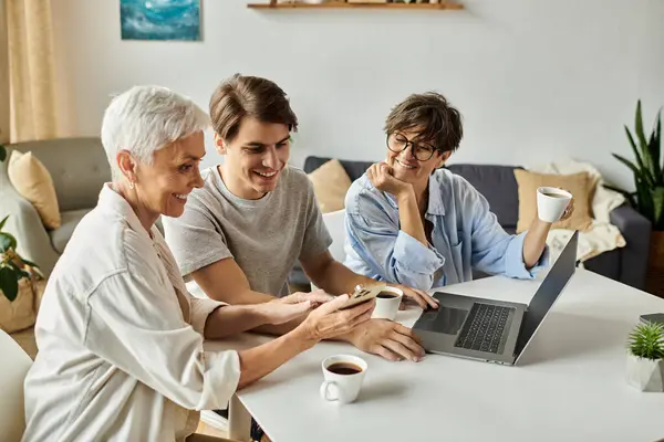 Lesbian parents and their adult son share laughter and warmth over tea in a bright, inviting space. — Stock Photo