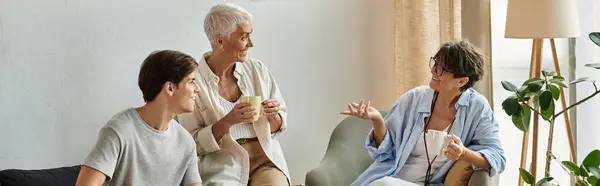 Lesbian parents and their adult son enjoy a warm conversation while sipping coffee together. — Stock Photo