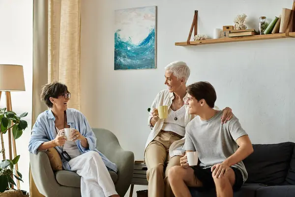 Lesbian parents and their adult son share laughter and love while sipping warm beverages in a cozy setting. — Stock Photo