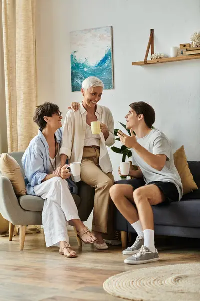 A loving LGBTQ family shares laughter and warmth while sipping drinks in their inviting living space. — Stock Photo