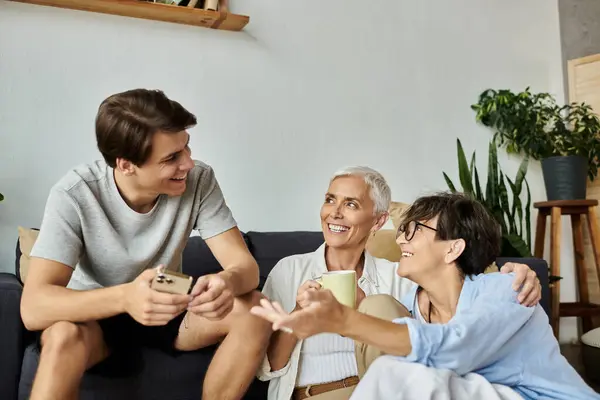 Eine liebevolle LGBTQ-Familie genießt einen freudigen Moment und teilt Lachen und Geschichten in ihrem gemütlichen Wohnzimmer. — Stockfoto