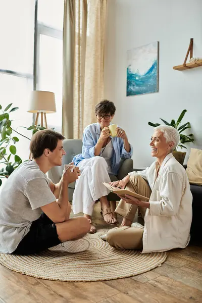 Une famille LGBTQ aimante partage des rires et des histoires dans son espace de vie accueillant, appréciant l'autre compagnie. — Photo de stock