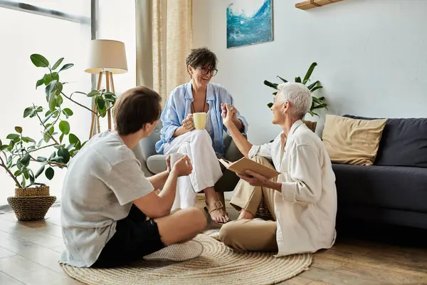 Lesbian parents and their adult son share laughter and stories in a warm, inviting living room. — Stock Photo
